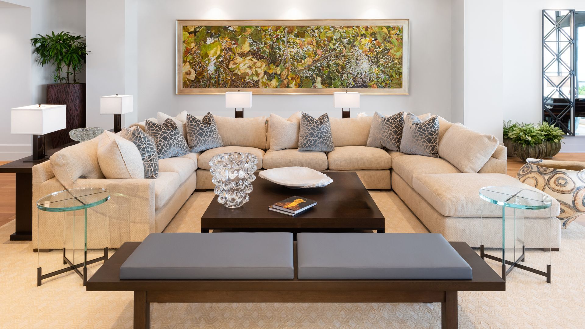 U-shaped beige sectional sofa with leopard print pillows, dark wood bench, and large abstract art in a modern living room.