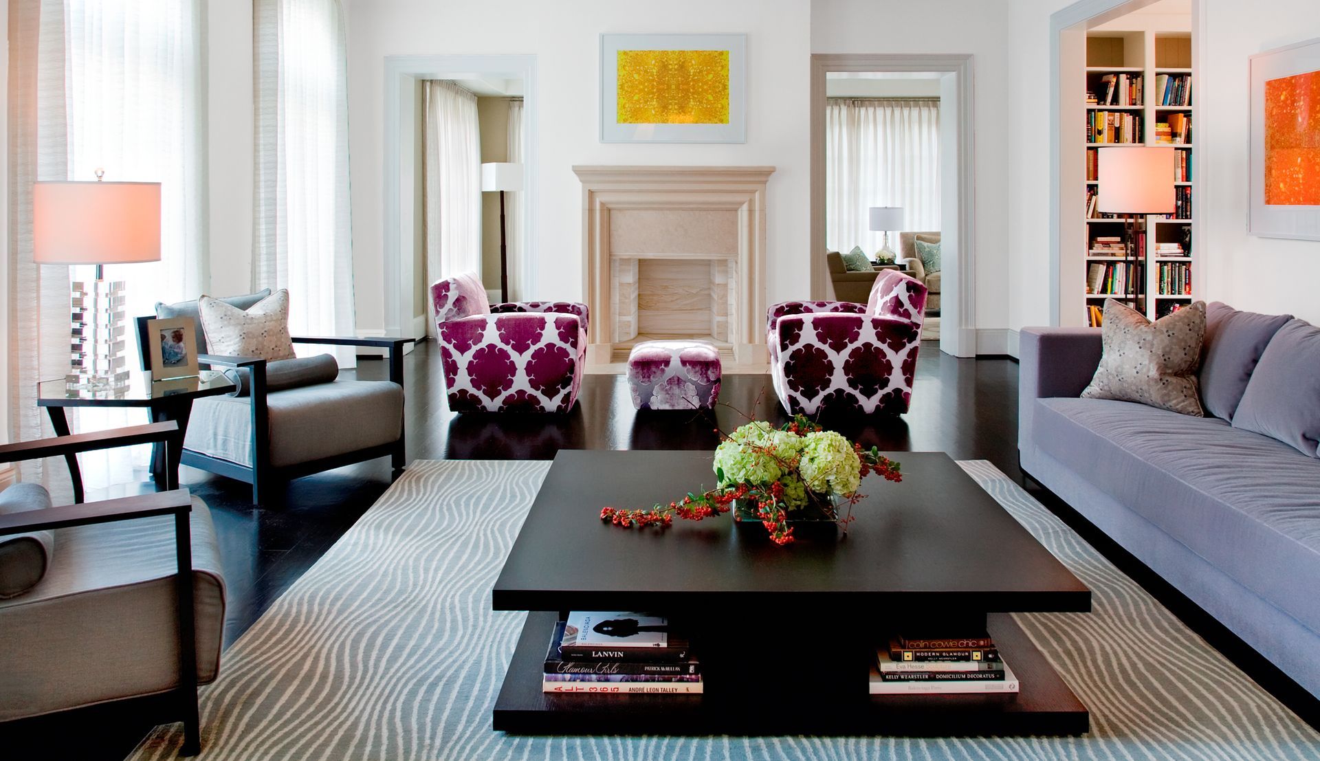 Living room with gray walls, modern furniture, and a fireplace; two patterned armchairs, a gray sofa, and black coffee table.