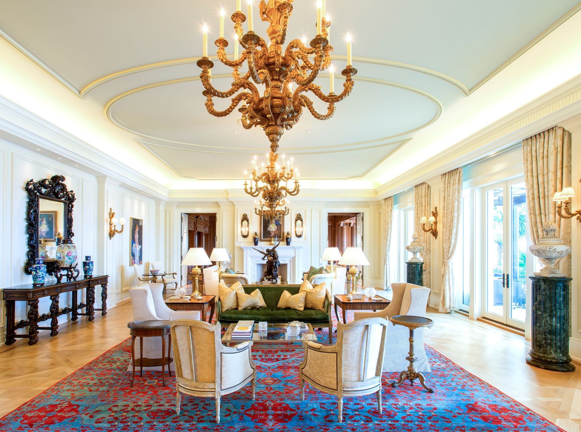 Ornate living room with chandelier, plush furniture, and a patterned rug.