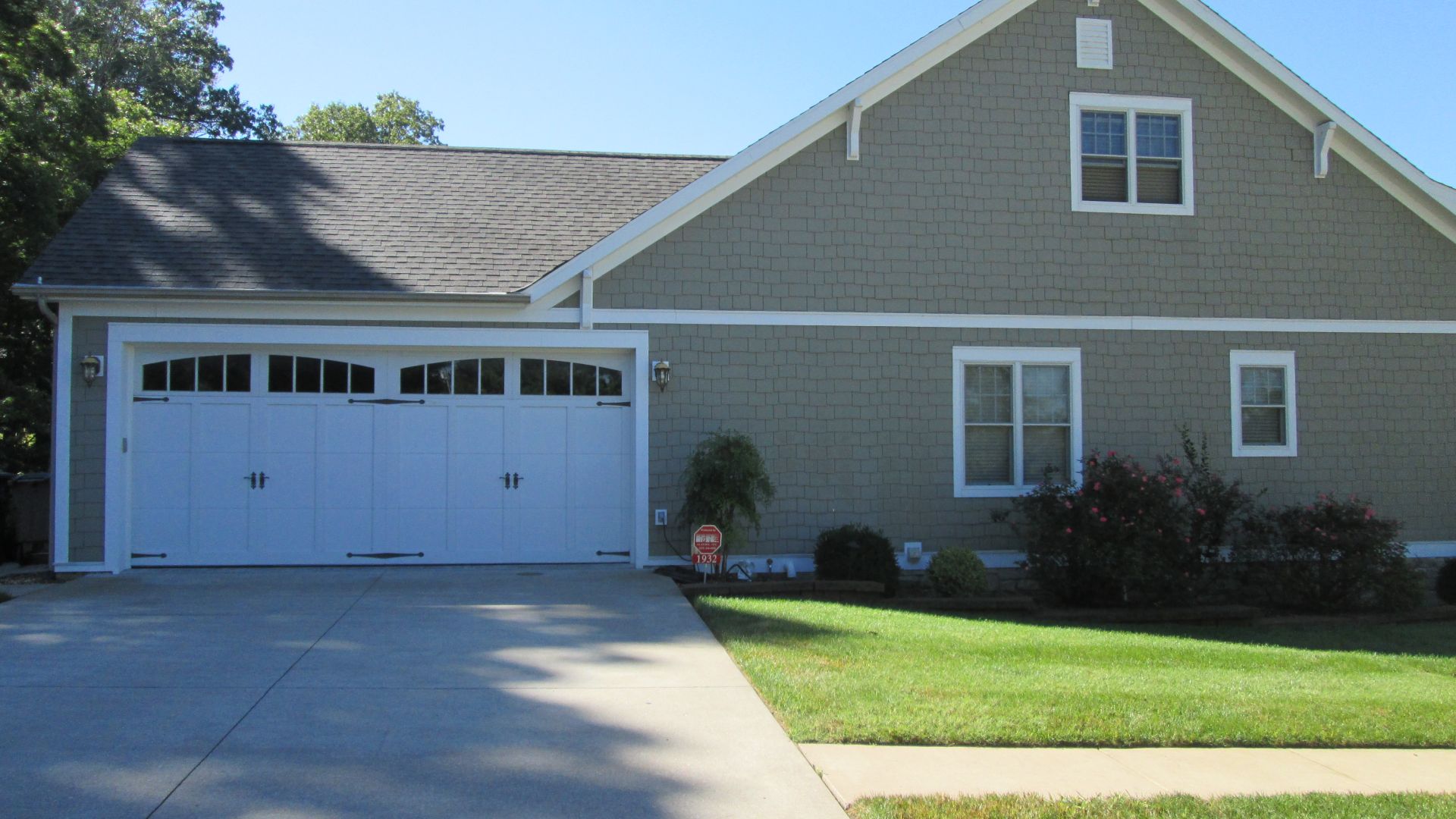Suburban house with white garage, gray siding, and a driveway in front