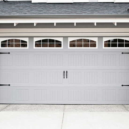 White garage door with four arched windows beneath a gray roofline
