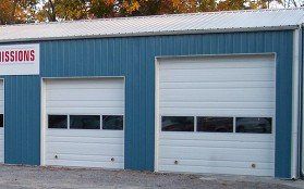 Blue building with two white garage doors, one small and one large, side by side.