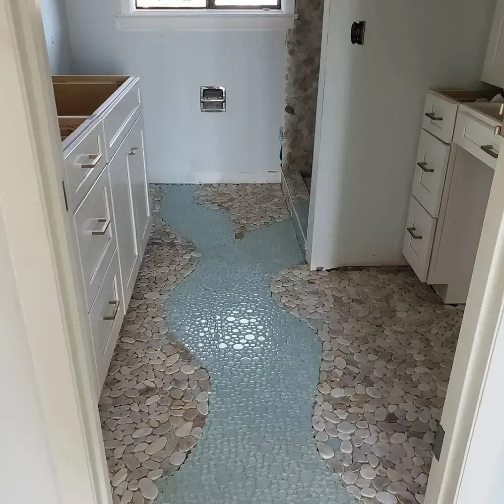 Bathroom with pebble stone flooring and a blue mosaic tile 