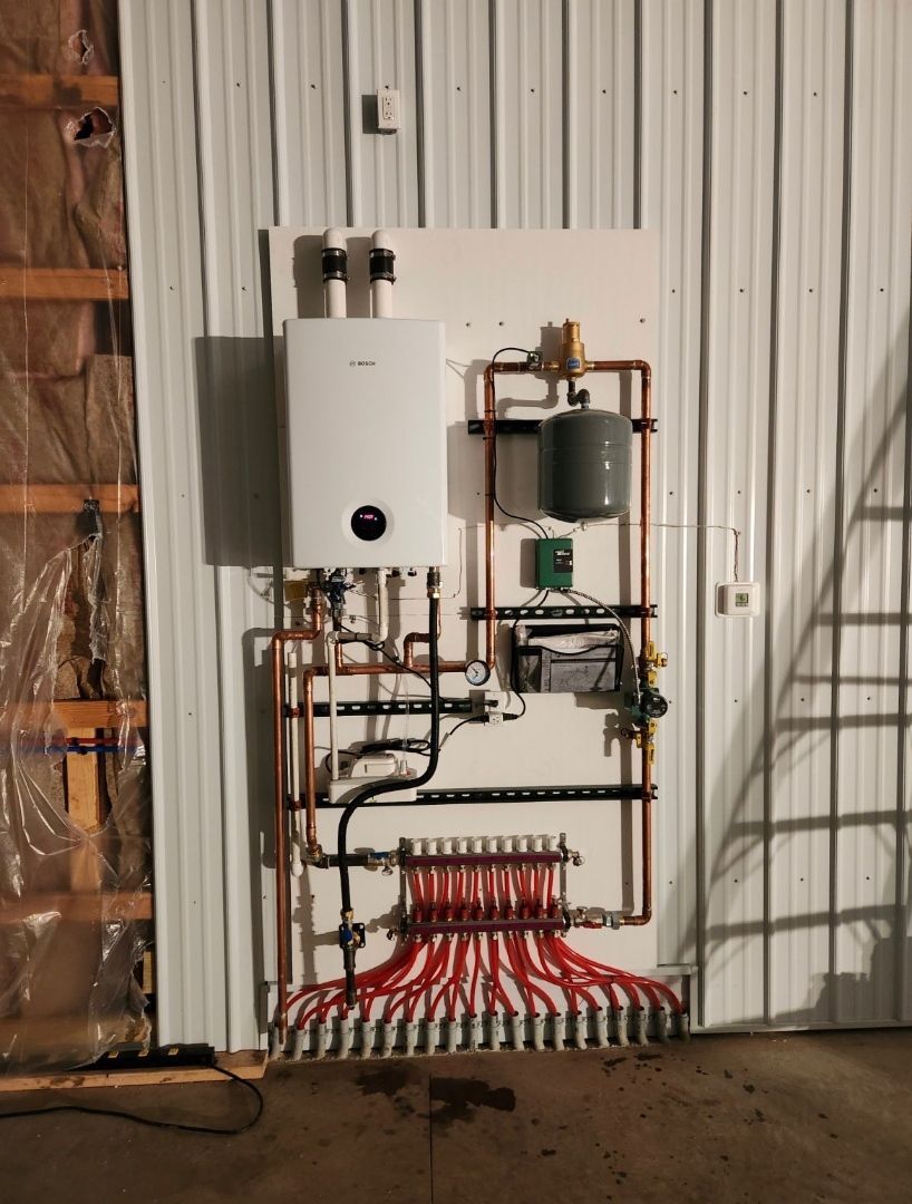 A wall with a boiler and pipes on it