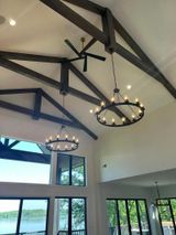 Lake-view room with exposed beams, chandelier lights, and large windows overlooking the water