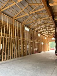 Interior of a wooden barn under construction with exposed framing and concrete floor