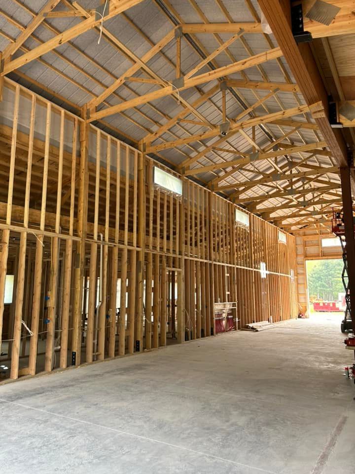 Interior of a timber-framed building under construction with exposed rafters and unfinished concrete floor