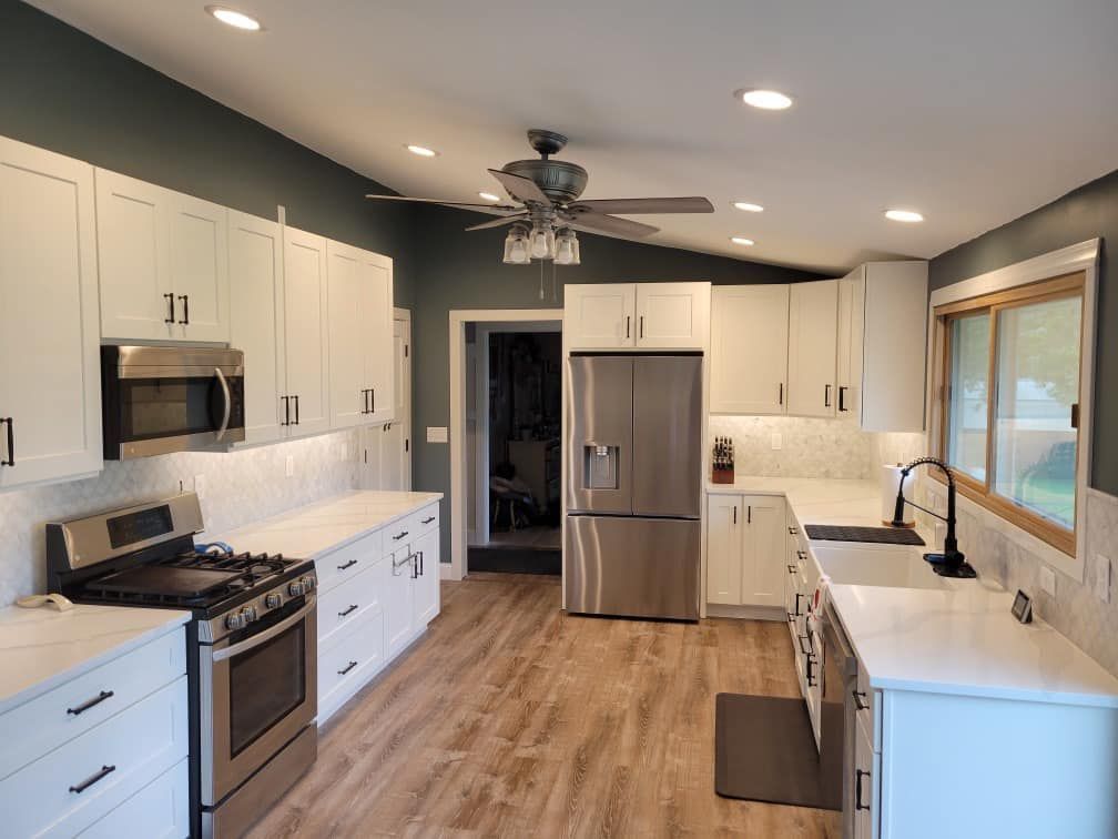 Bright modern kitchen with white cabinets, stainless appliances, island sink, and wood floors