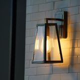 Wall-mounted lantern with warm light against a white tiled wall