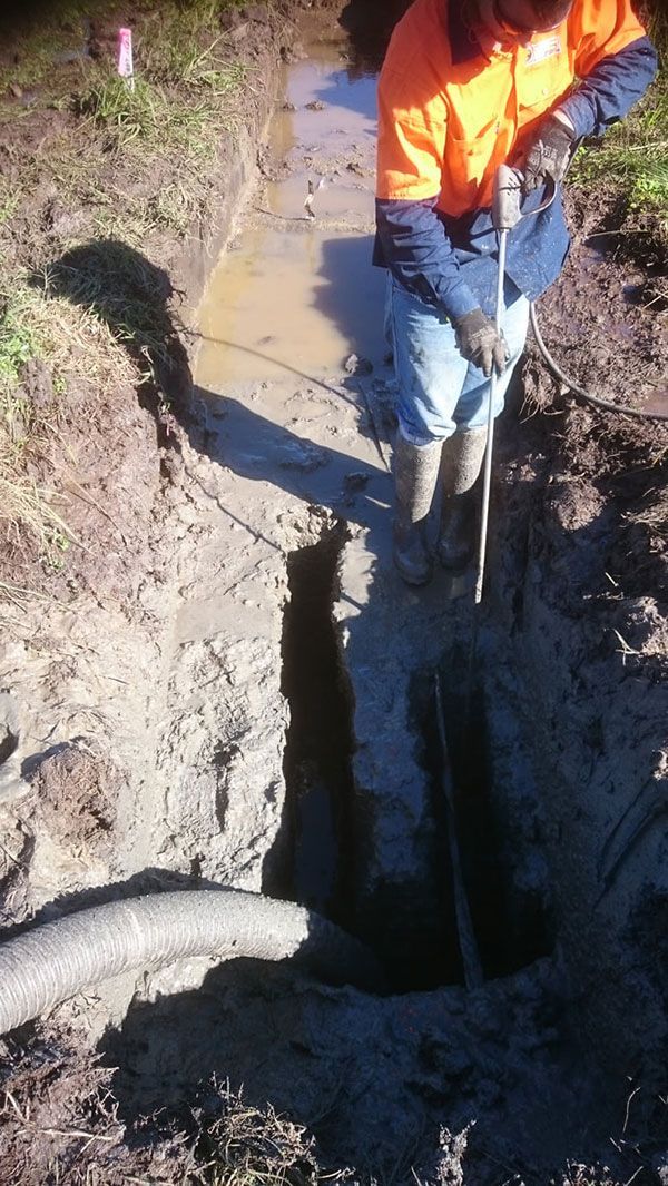 A man is digging a hole in the dirt with a shovel.