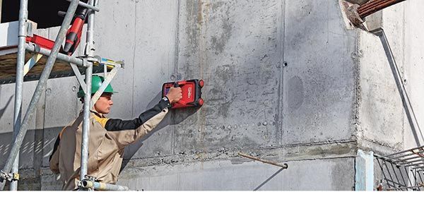A construction worker is working on a concrete wall.