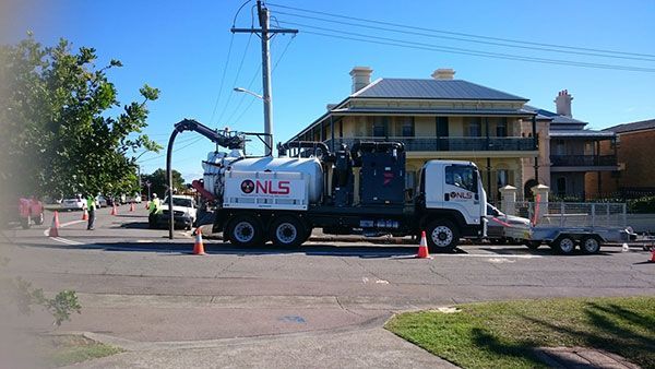 A vacuum truck is parked on the side of the road in front of a house.