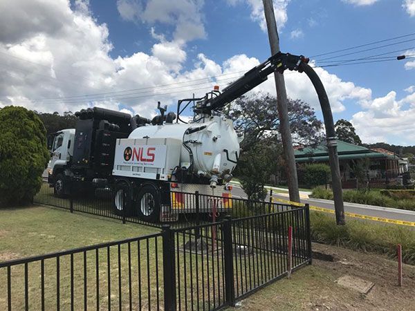 A vacuum truck is parked in front of a fence.