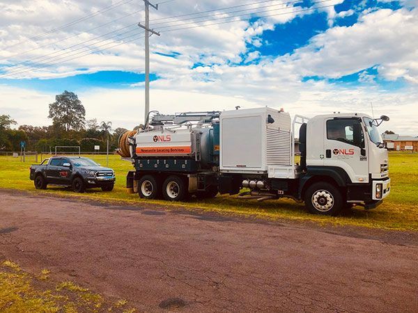 A vacuum truck is parked next to a car on the side of the road.