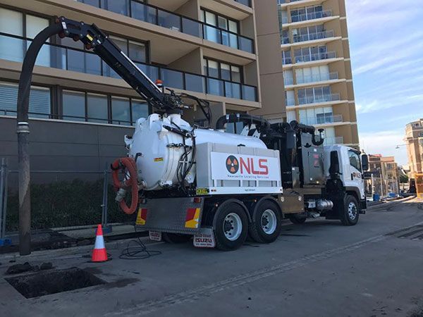 A vacuum truck is parked in front of a building.