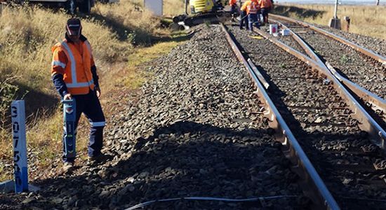 A man is standing on the side of a train track.