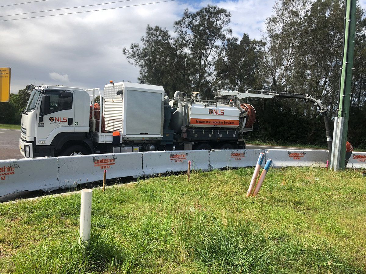 A white truck with a vacuum cleaner attached to it is parked on the side of the road.