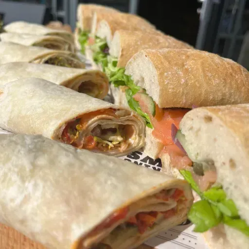 Diverse wraps met sla en tomaat, uitgestald op een dienblad.