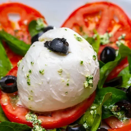 Caprese salade met mozzarella, tomatenschijfjes, basilicum en zwarte olijven