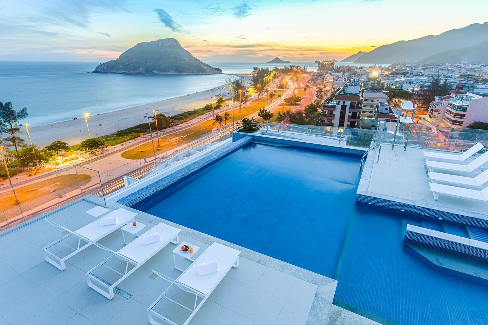 Há uma grande piscina no telhado de um prédio com vista para o oceano.