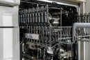 The upper rack of an empty, clean dishwasher with grey, metallic wire shelving and a grey handle.