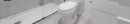 A modern bathroom featuring a white toilet next to a glass-enclosed walk-in shower with light grey tiled walls.