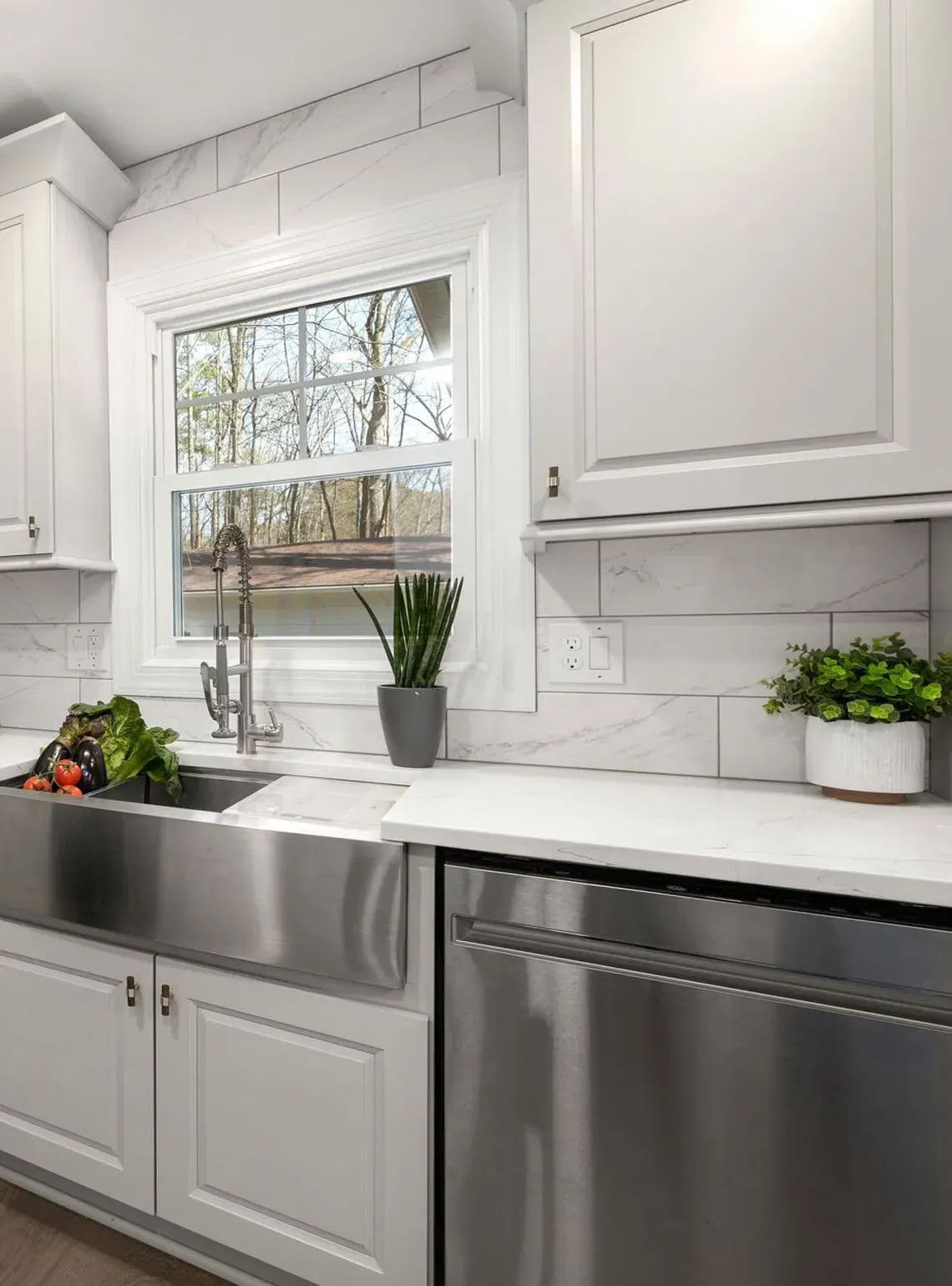 Modern kitchen with white cabinets, stainless steel appliances, a farmhouse sink, and white subway tile backsplash.