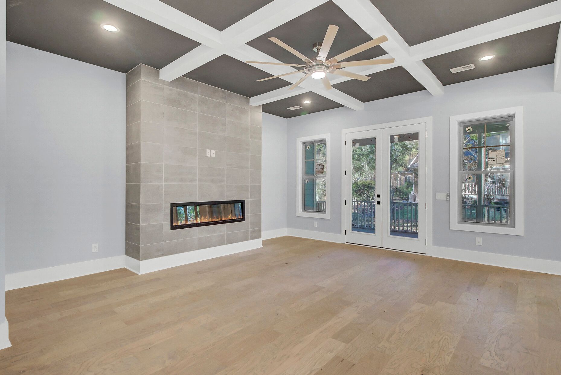 An empty living room with a fireplace and a ceiling fan.