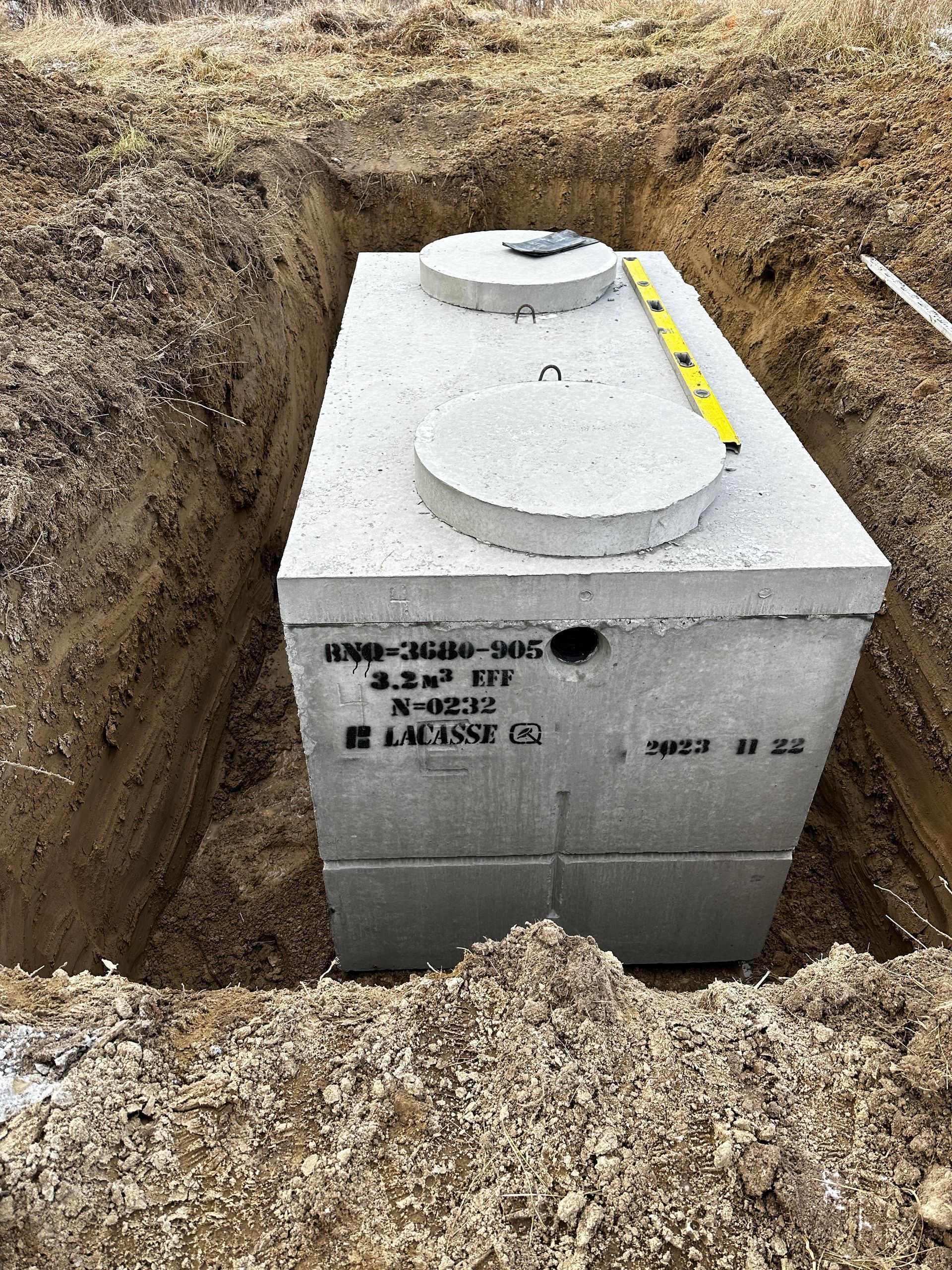 Fosse septique en béton dans une tranchée excavée, prête à être installée.