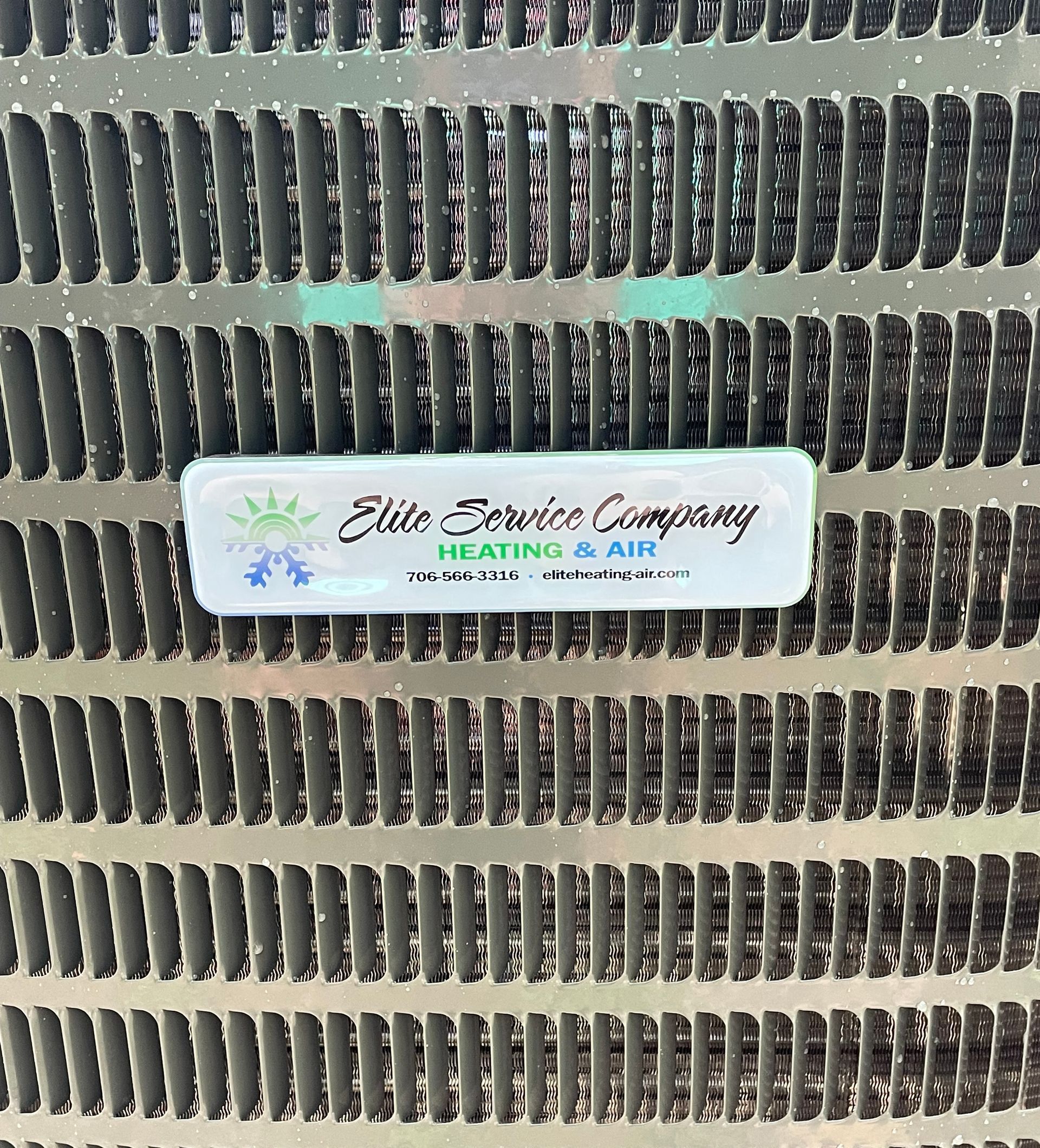 A close up of a grille with a label on it that says elite service company heating and air.