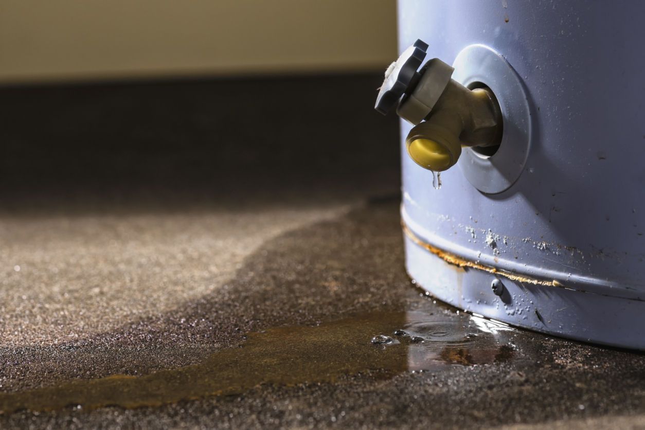 A water heater is leaking water on the floor.