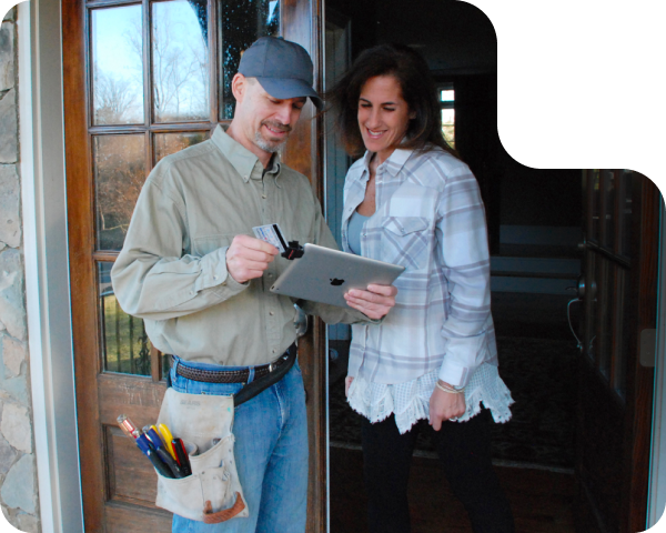 Man in cap and woman at doorway reviewing paperwork.