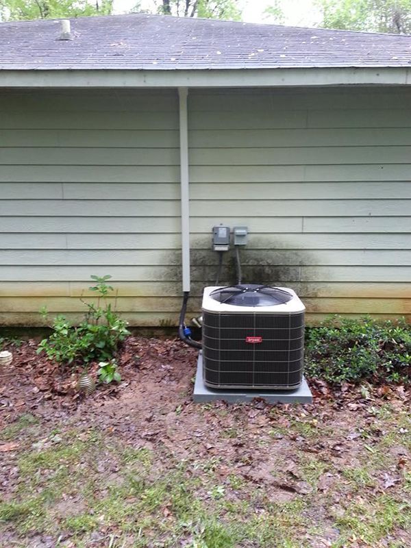 An air conditioner is sitting on the side of a house.