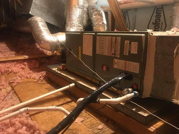 An air conditioner is sitting in the attic of a house.