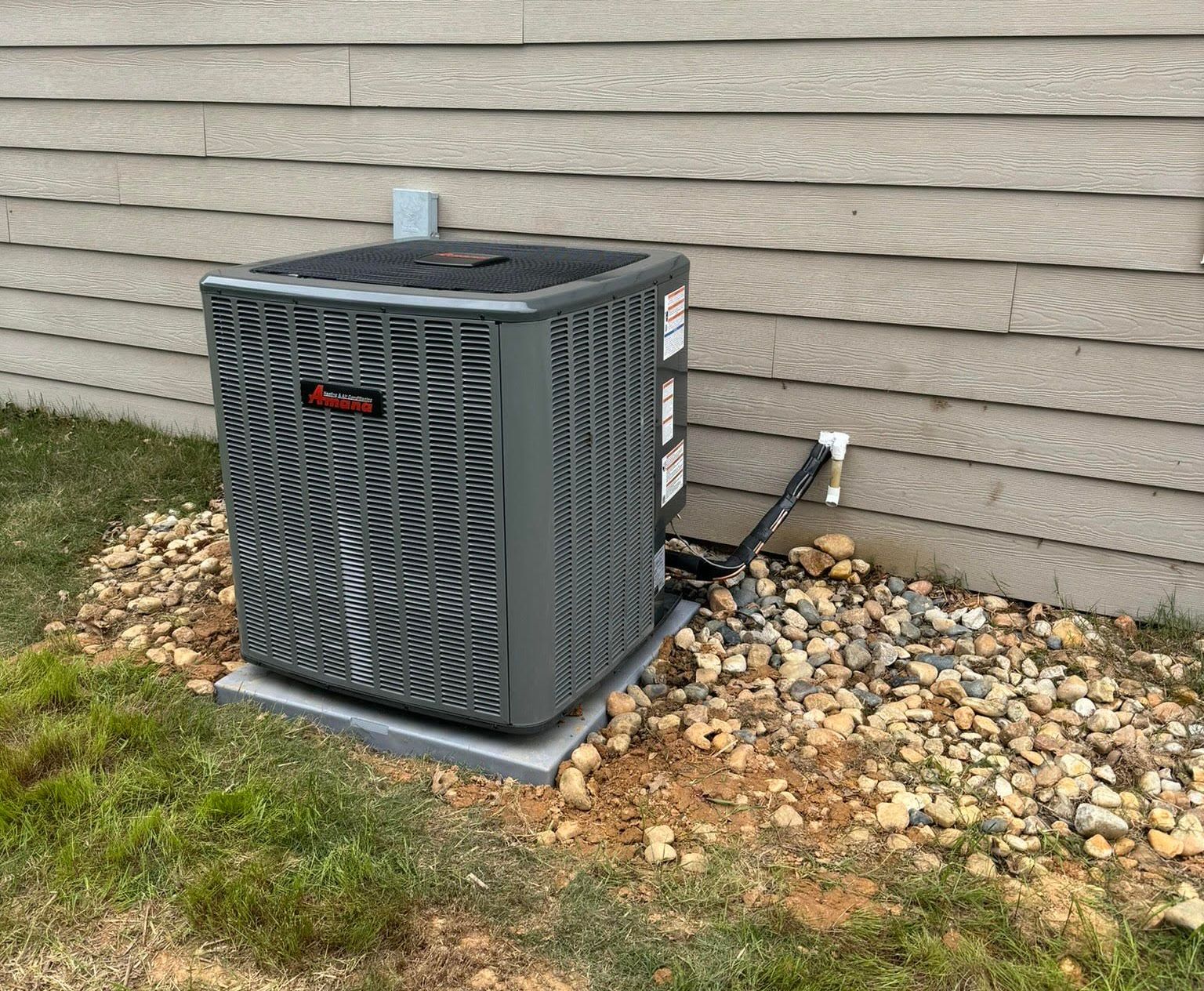 An air conditioner is sitting on the side of a house.