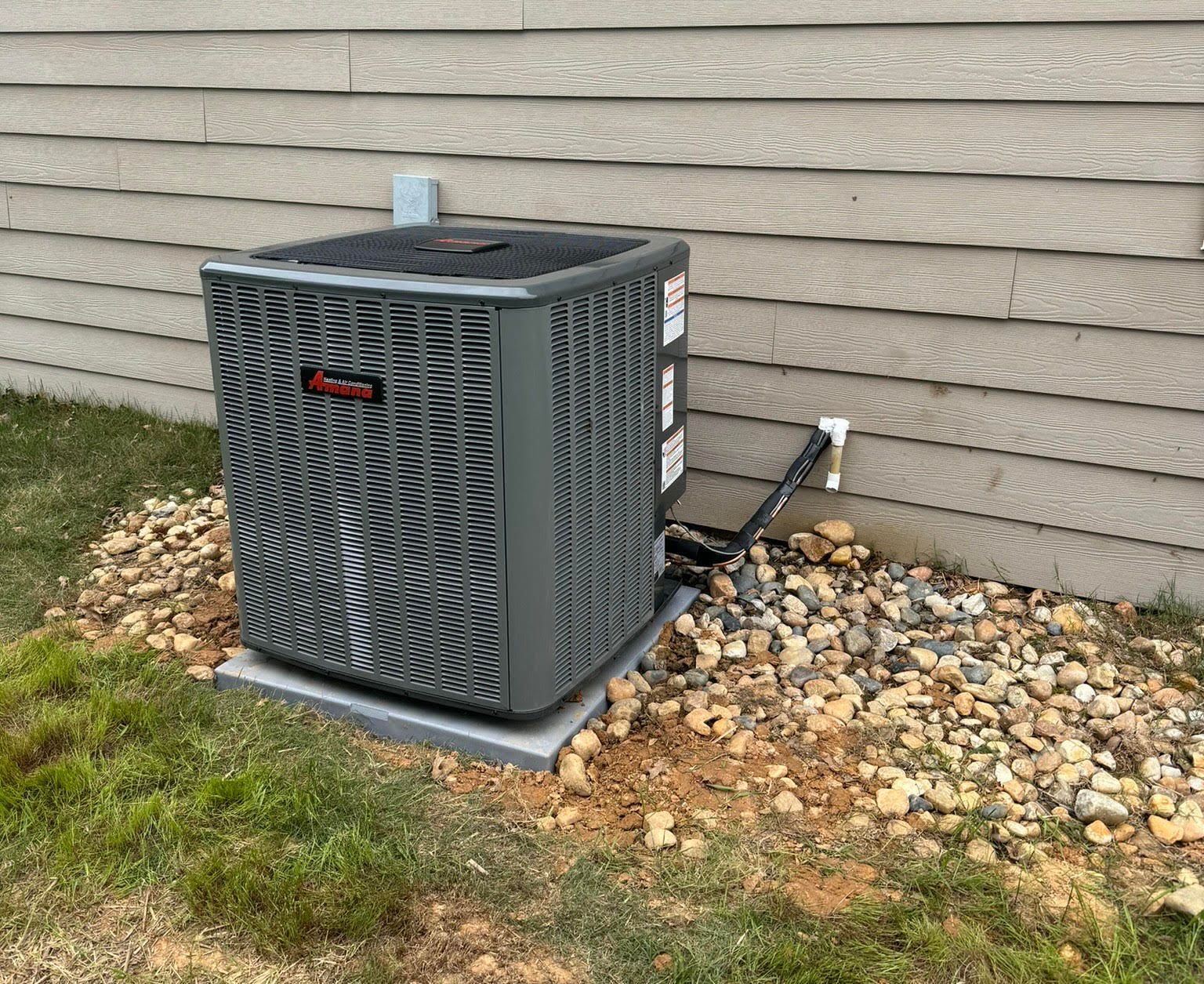 An air conditioner is sitting on the side of a house.