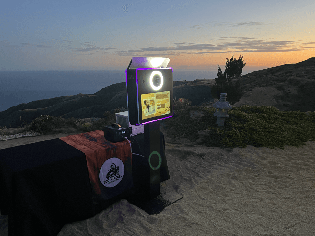 A photo booth is sitting on top of a sandy hill.