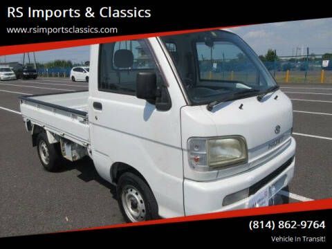 A white Japanese mini truck parked in a large lot, with text overlaid for RS Imports & Classics and a phone number.