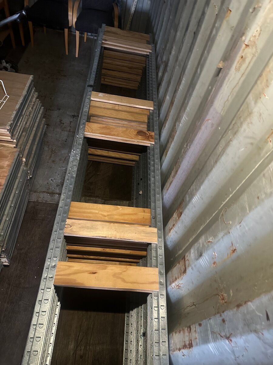 A long, vertical view of wooden slats arranged in a metal frame inside a corrugated storage container.