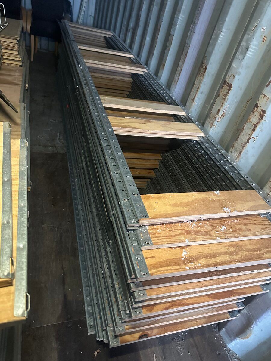 A stack of rectangular metal frames with wooden panels, stored horizontally in an industrial container.