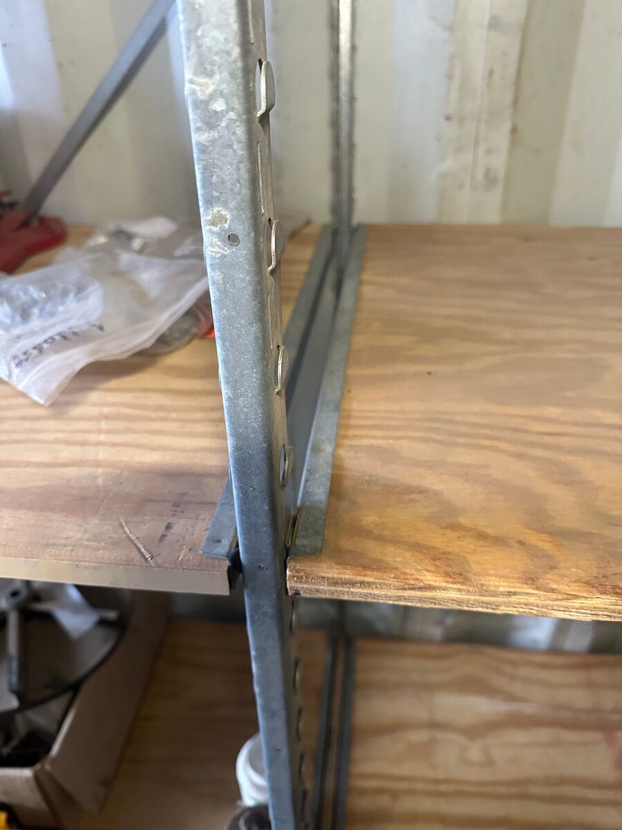 A close-up view showing metal shelving uprights with wooden shelf boards resting on integrated metal supports.