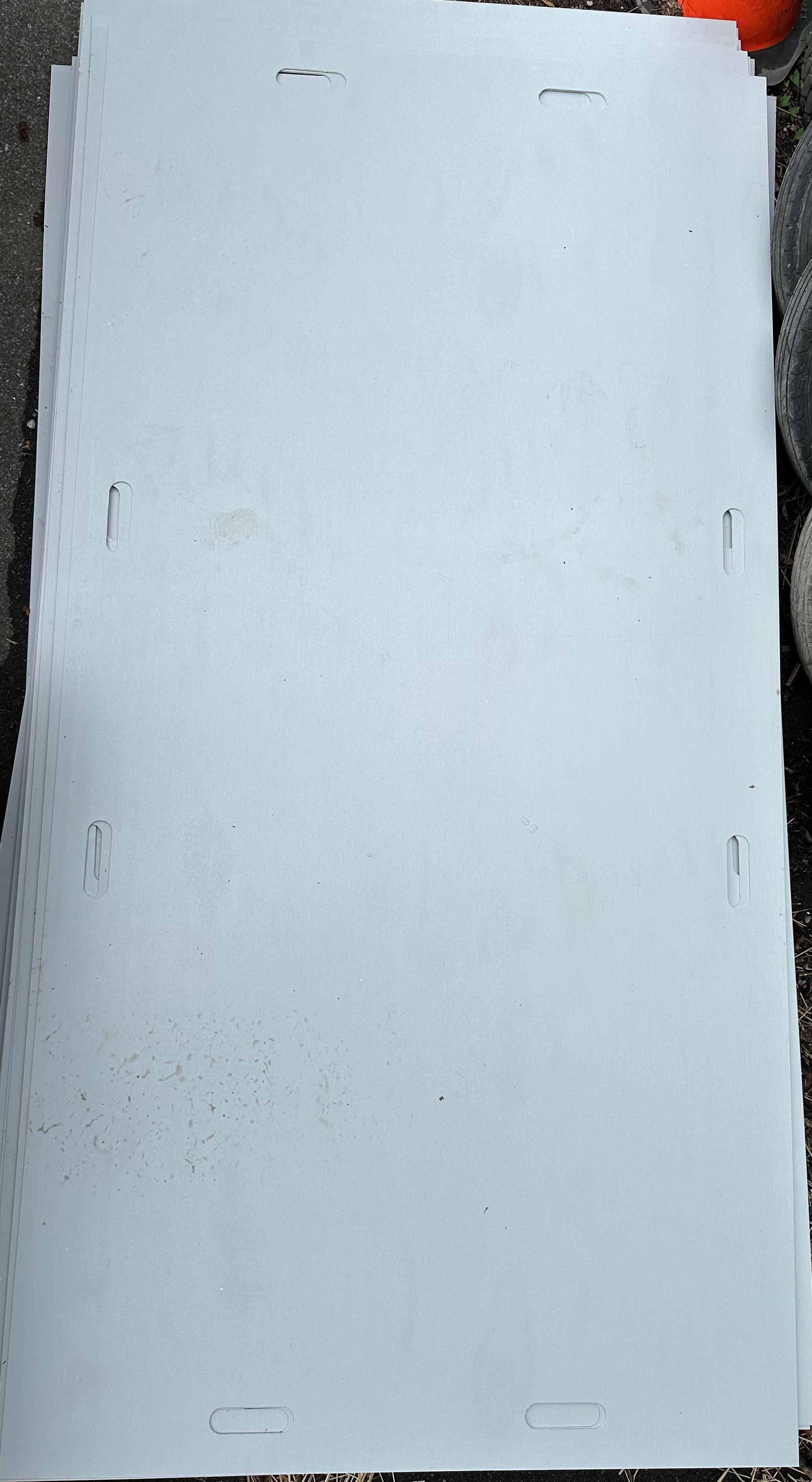 A stack of rectangular, off-white cardboard sheets with die-cut slots along the edges, resting on a textured surface.