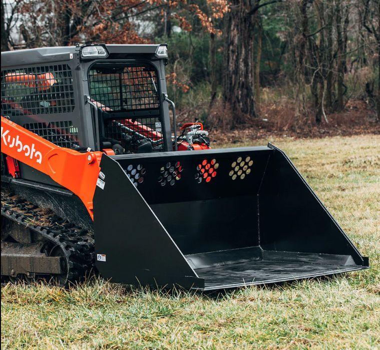 An orange Kubota compact track loader with a large black bucket attachment parked in a field.