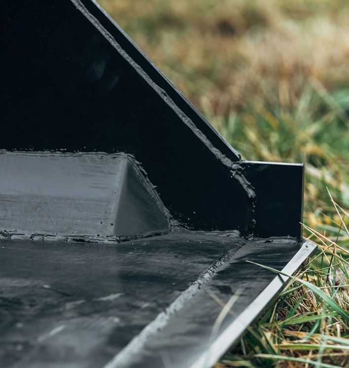 A close-up view of heavy-duty black metal equipment, showing thick welded joints and a triangular reinforced brace.