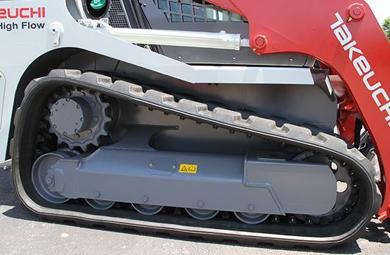Close-up of the grey undercarriage and black rubber track of a red Takeuchi compact track loader.