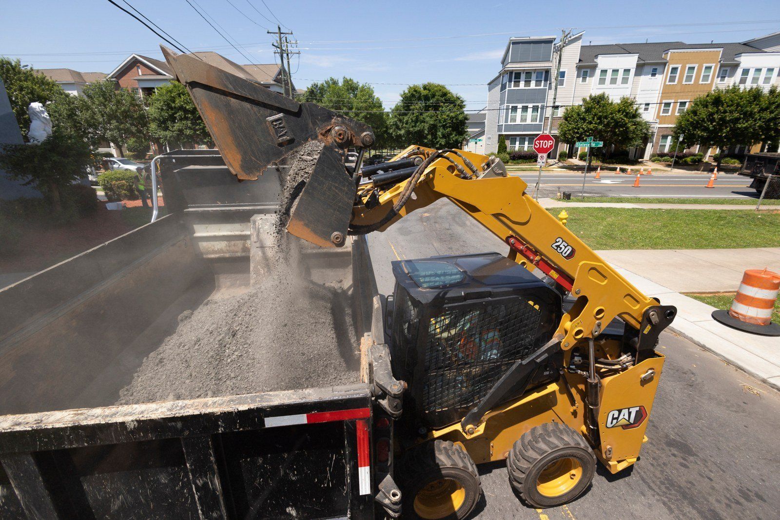 Cat 250 skid steer loader loading a dump truck — Flex Equipment Rental
