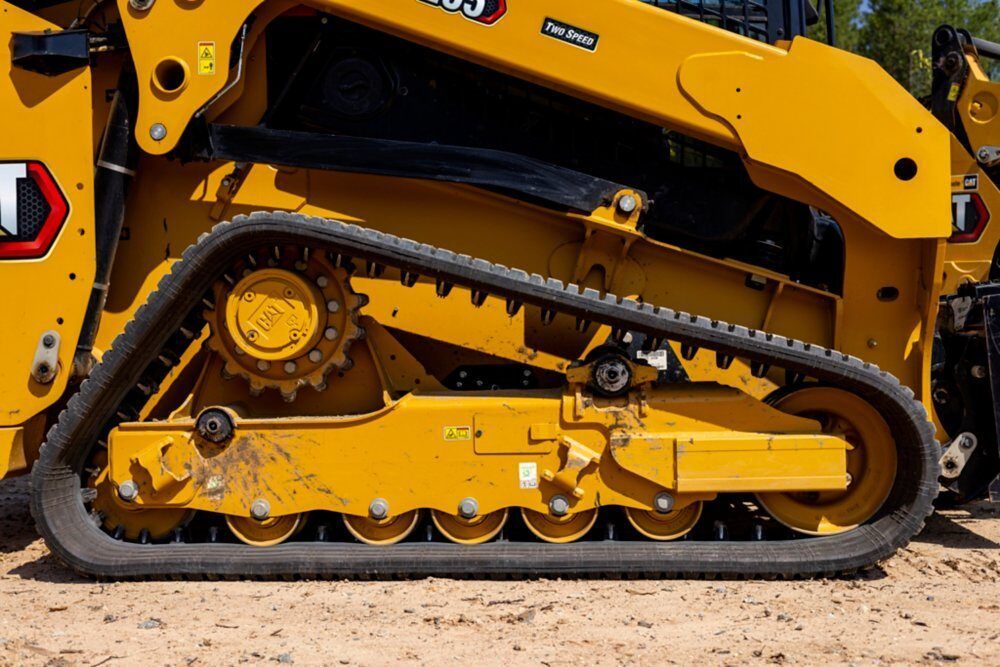 A yellow RT-90 compact track loader with a stump grinder attachment works on a dirt construction site.