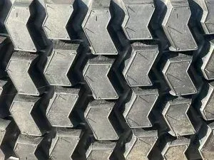 Close-up, top-down view of heavy-duty tire treads featuring a repeating chevron pattern in dark, textured rubber.