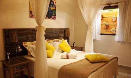 Um quarto com cama de dossel e travesseiros amarelos.