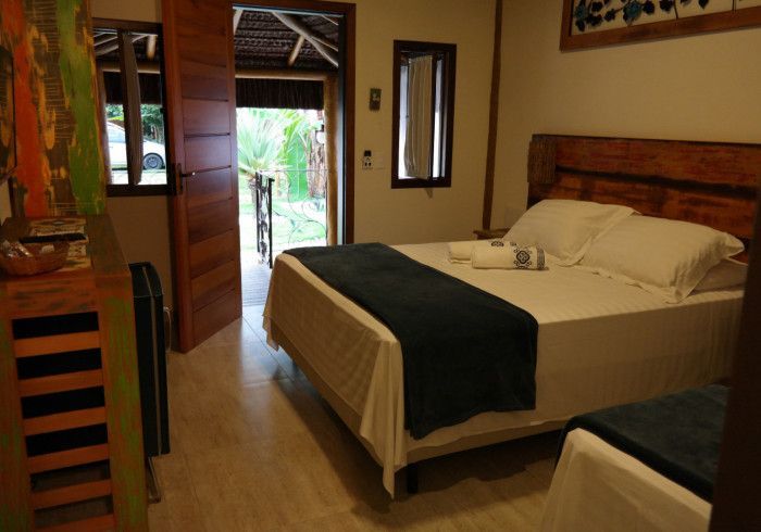 Um quarto com cama king size e duas camas de solteiro